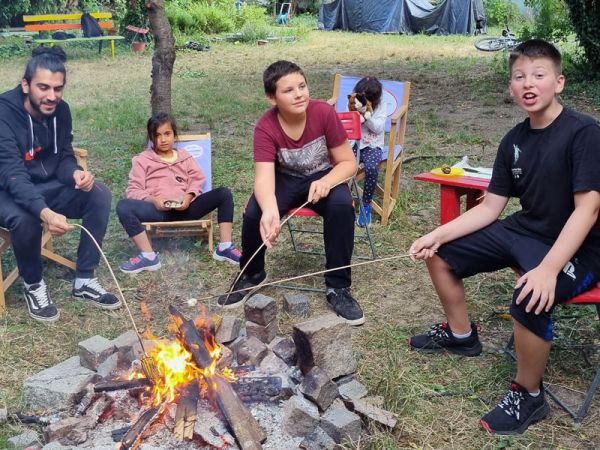 Eine Gruppe von Kindern sitzt um ein Lagerfeuer im Balugarten